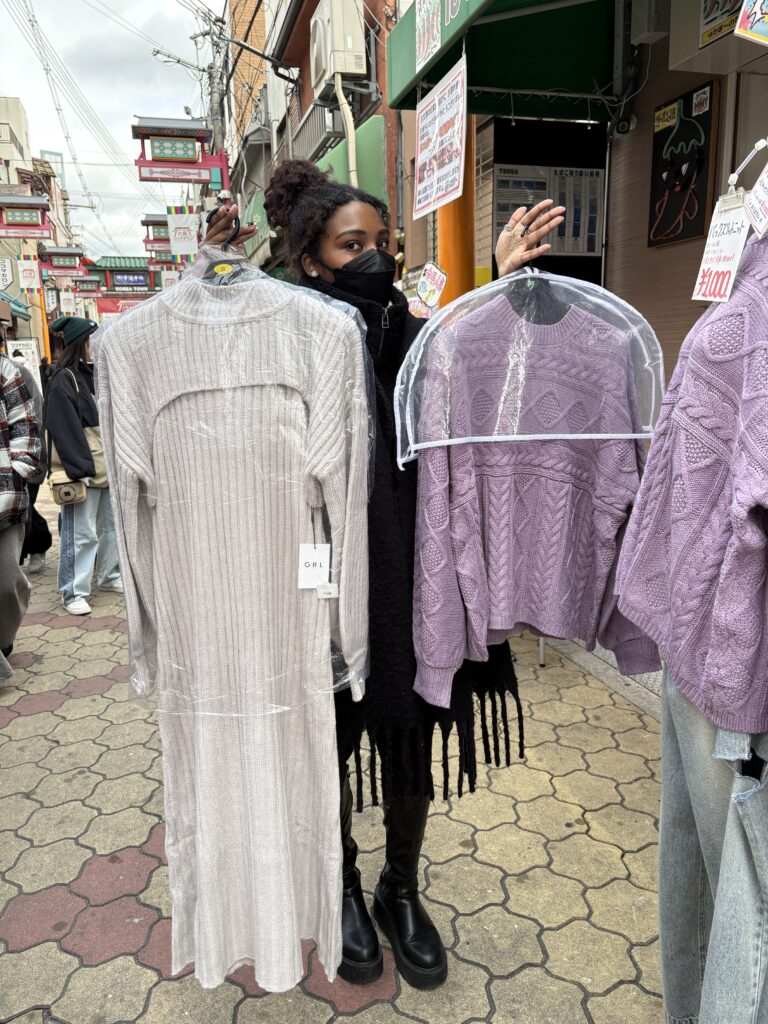 Woman holding two trendy knit sweaters on Miyuki-dori Shopping Street in Osaka Koreatown