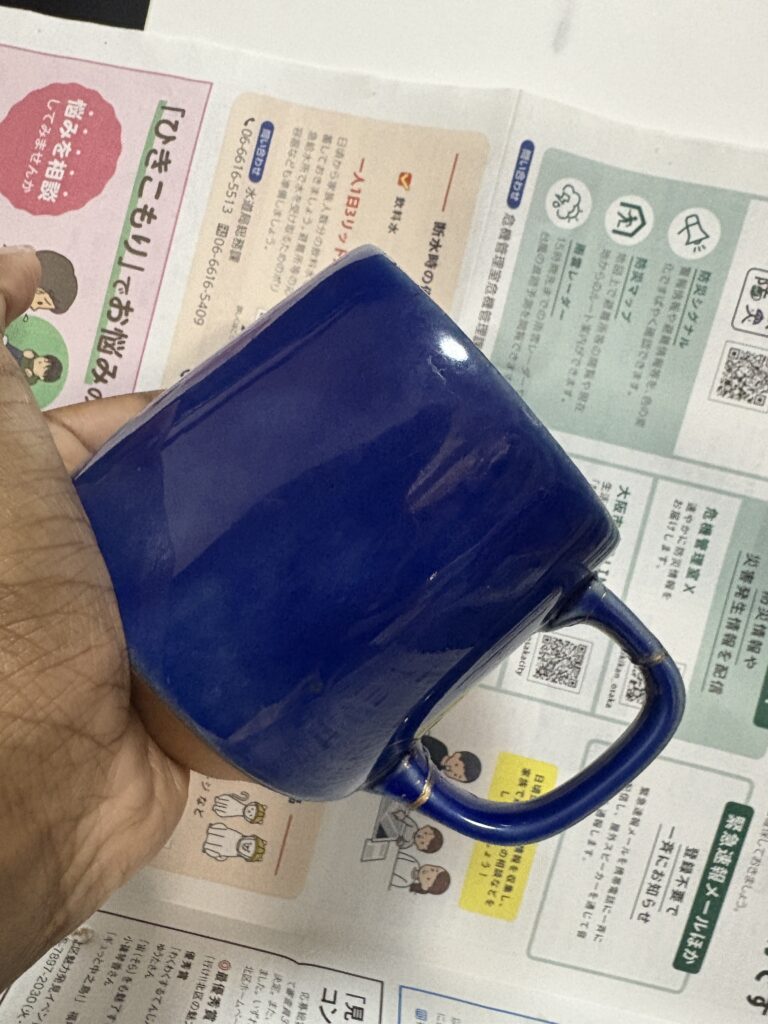 Repaired blue ceramic mug with visible gold seams highlighting the cracks in a Kintsugi-inspired finish.