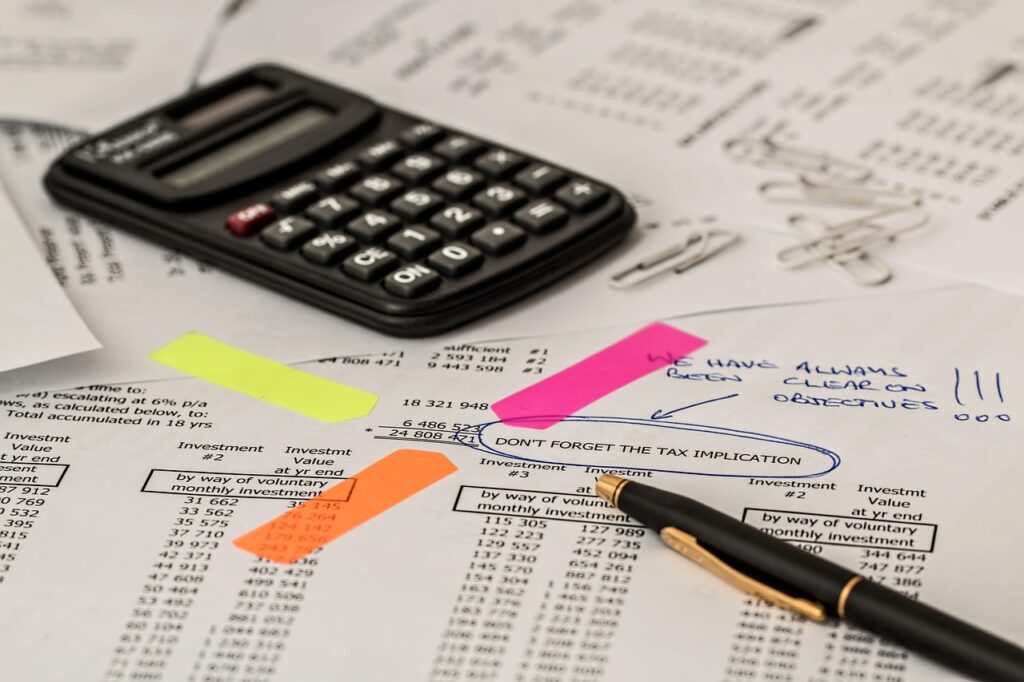 Calculator and pen on financial statement with bar graph