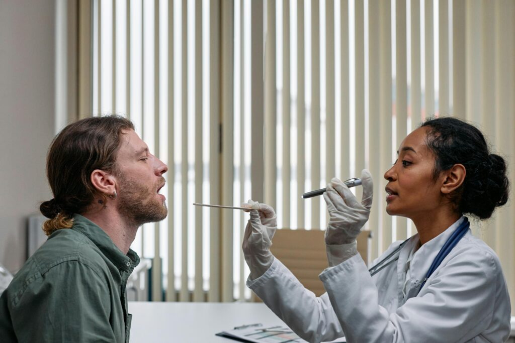 Doctor examining a patient’s throat with a tongue depressor and penlight