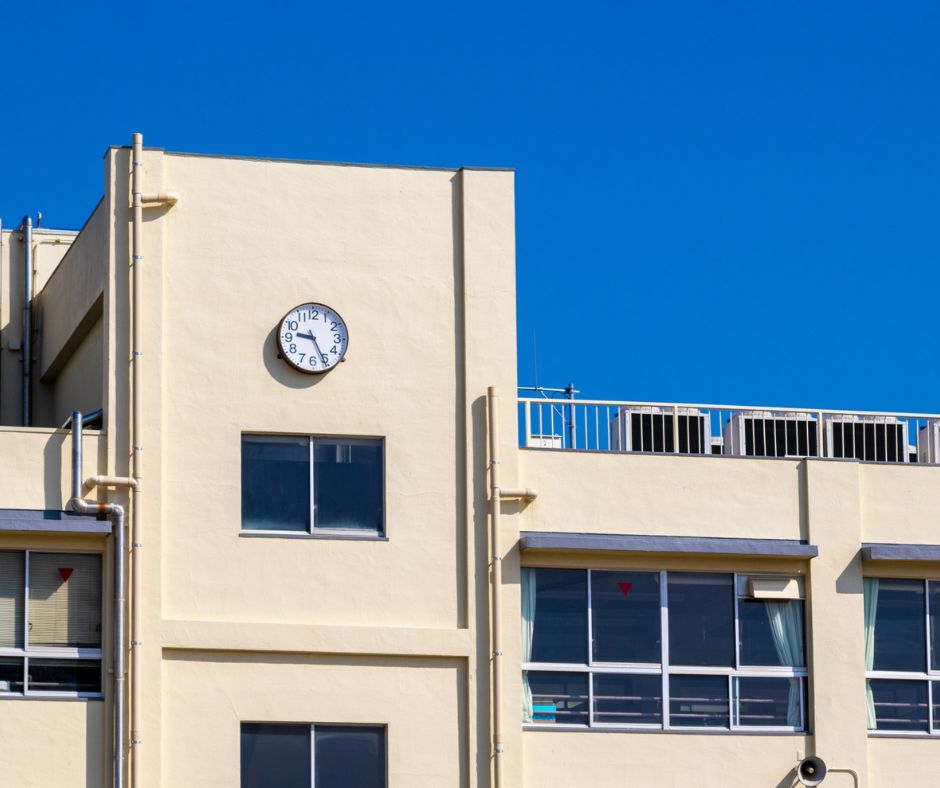 School building in Japan with a wall clock under a clear blue sky