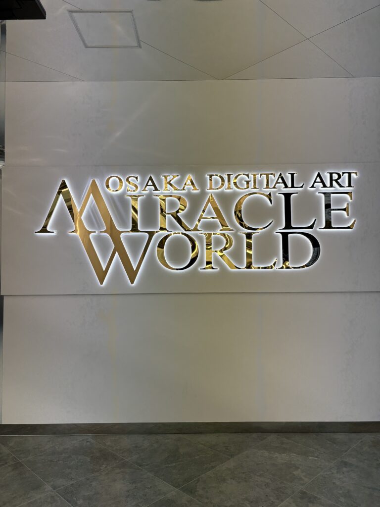 Entrance sign of Osaka Digital Art MIRACLE WORLD displayed on a clean white wall