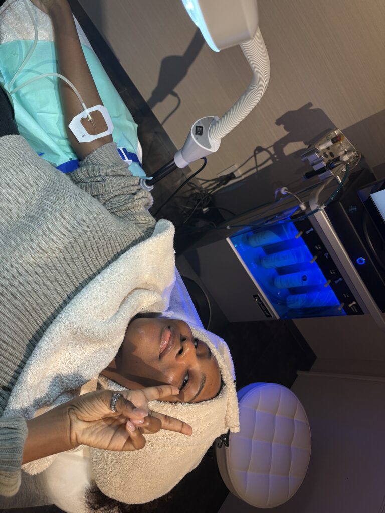Woman relaxing during a beauty treatment at a Japanese clinic while receiving an IV-style injection and facial care.