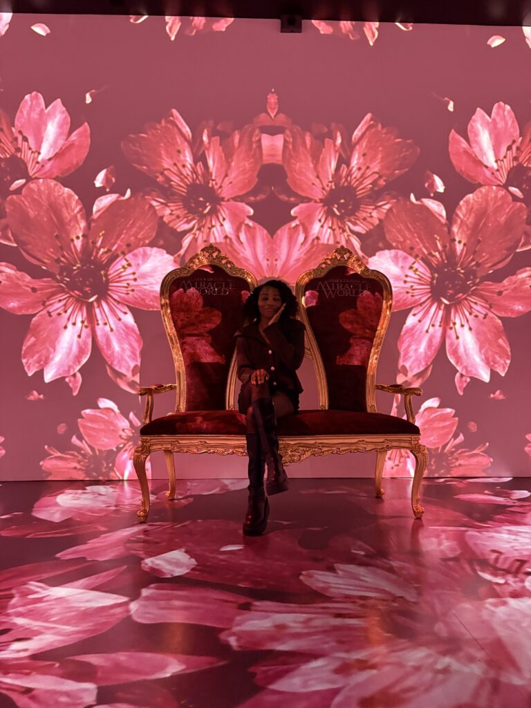 Visitor walking through mirrored room with colorful LED floral visuals reflecting across walls and floor