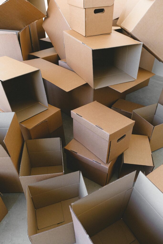 Large pile of empty cardboard moving boxes stacked and scattered across a room.