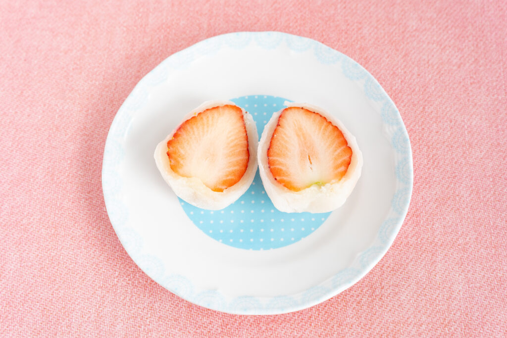 Ichigo daifuku cut in half showing a juicy Japanese strawberry inside soft mochi.