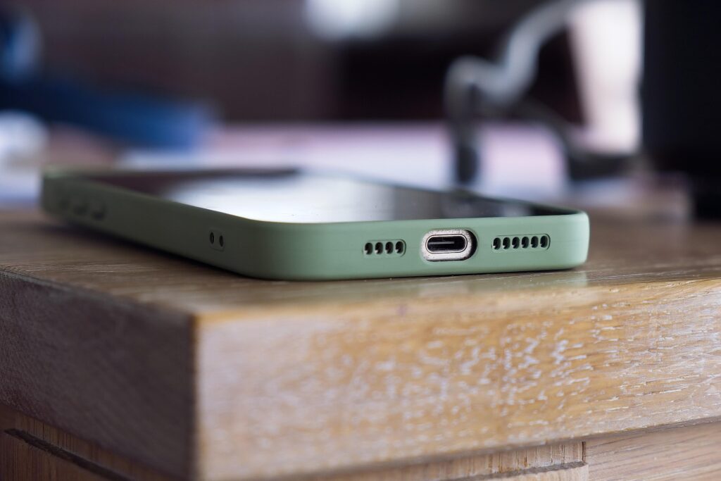 Close-up of a smartphone with a green case lying on the edge of a wooden table