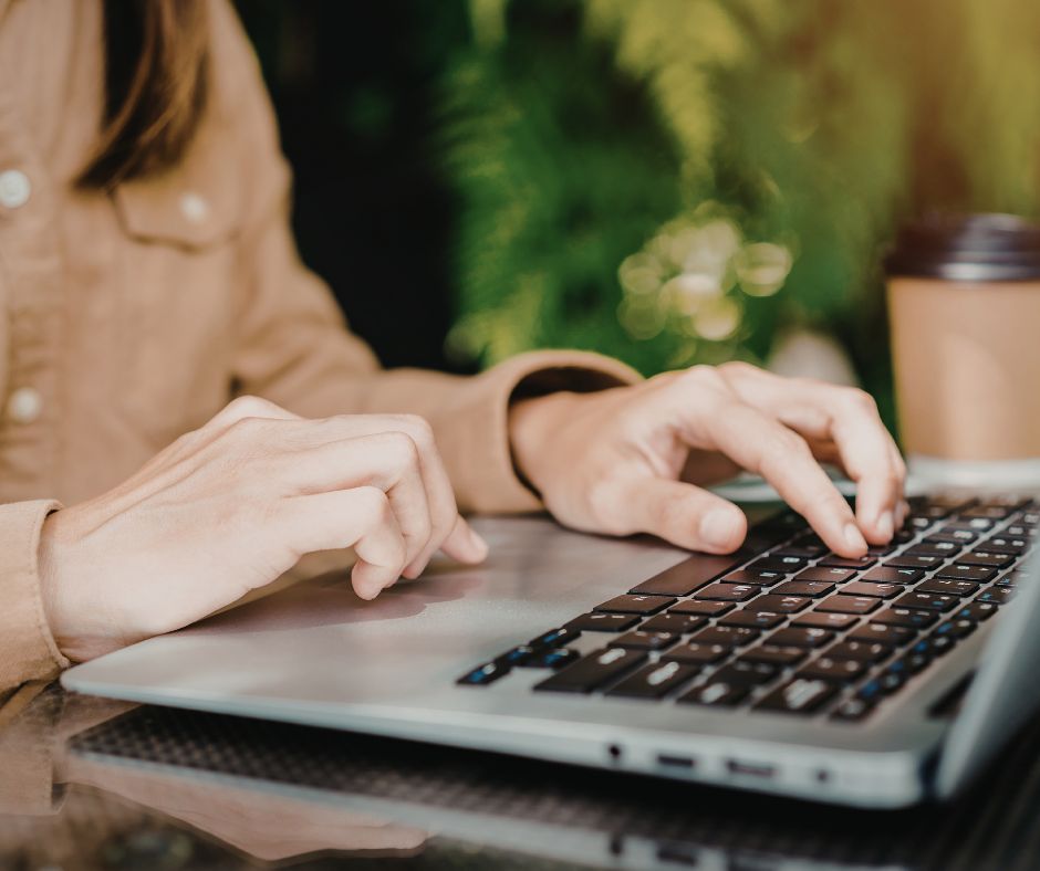 Person typing on a laptop in a café, representing remote work during a commute delay