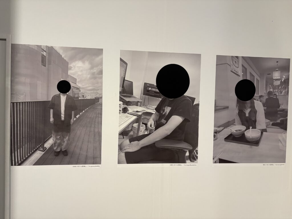 Three monochrome portrait photographs with black circles covering the faces displayed on a gallery wall