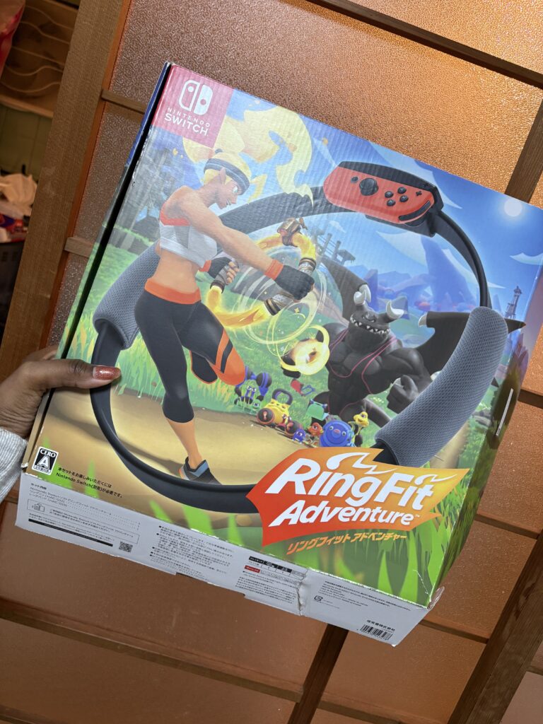 Hand holding a Nintendo Switch Ring Fit Adventure box indoors.