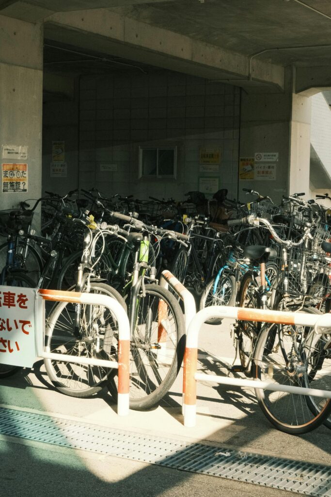 A crowded covered bicycle parking space filled with different bikes under an apartment or building structure
