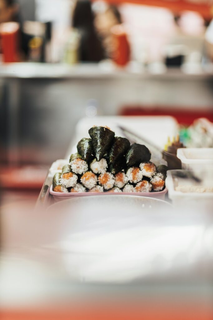 Stack of freshly made makizushi rolls wrapped in nori displayed at a sushi counter