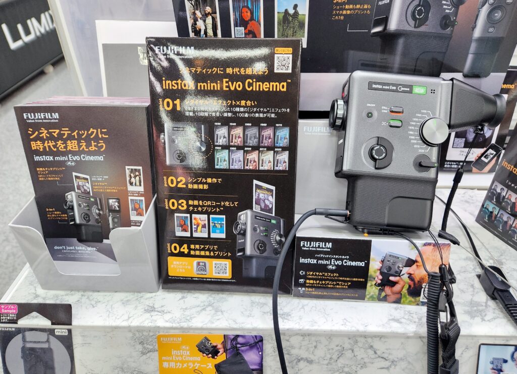 Fujifilm Instax Mini Evo Cinema display at CP+ 2026, featuring the retro-style hybrid instant camera, promotional signs, and sample materials at the booth.
