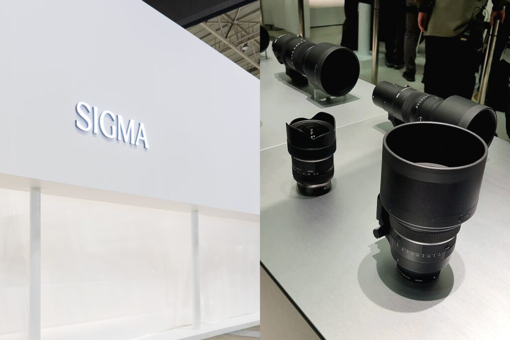 Sigma booth display at CP+ 2026 with a clean white wall logo and a selection of premium Sigma lenses showcased on a counter.
