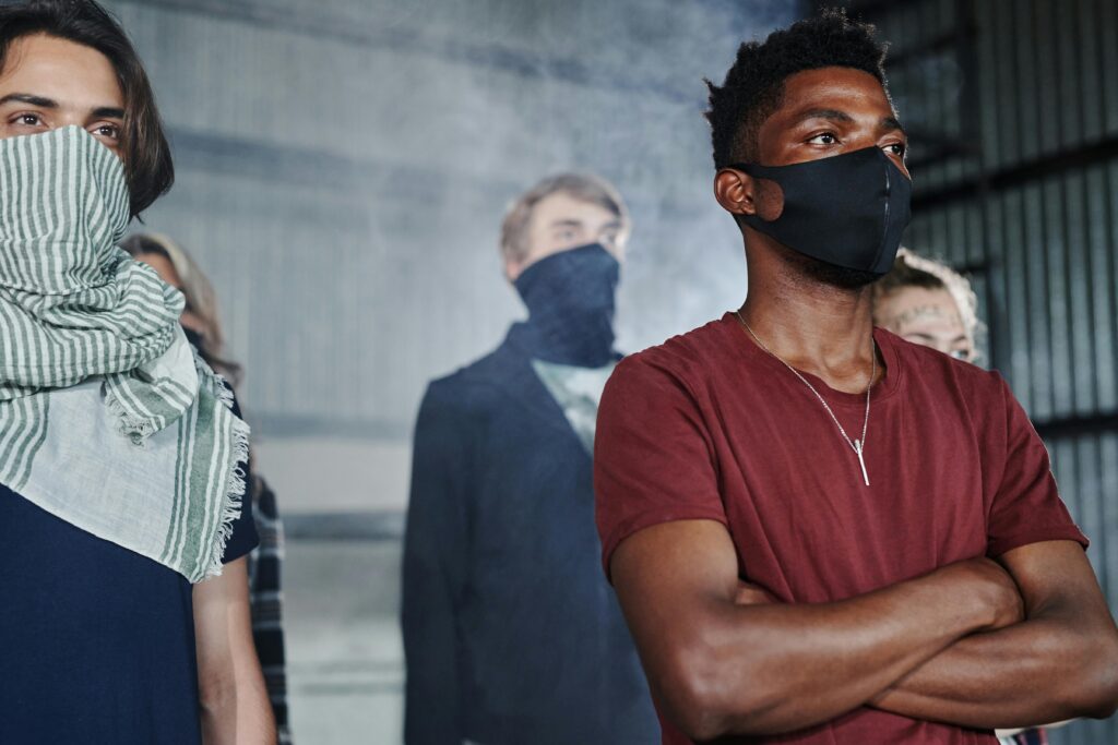 Person wearing a face mask while holding a yellow flower close to their face, symbolizing spring allergies and pollen sensitivity.