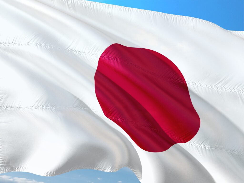 A close-up of the Japanese flag waving in the wind against a clear blue sky
