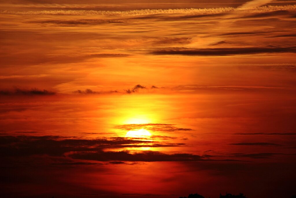 Bright orange summer sunset with dramatic clouds across the sky, representing the intense heat of Japanese summer.
