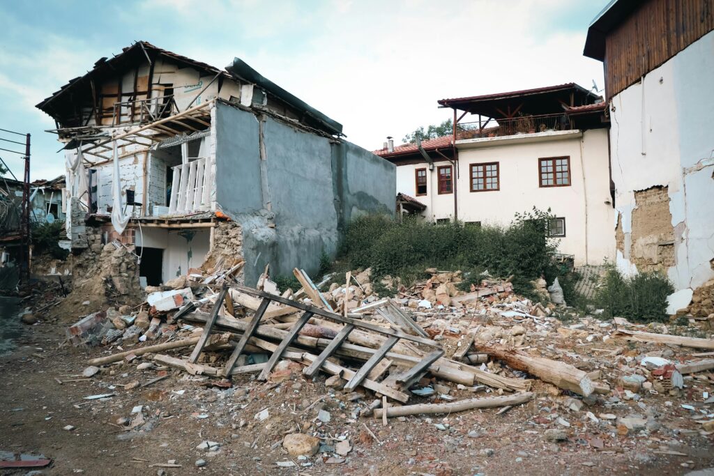Damaged residential houses surrounded by rubble and debris after an earthquake.