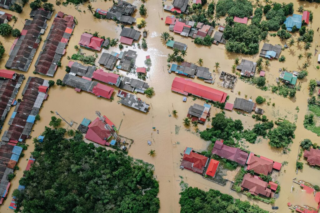 Aerial view of severe flooding covering homes and streets, showing the impact of heavy rain and flood risks during extreme weather.