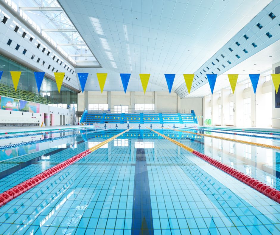 Indoor public swimming pool in Japan with multiple lanes and bright natural lighting.
