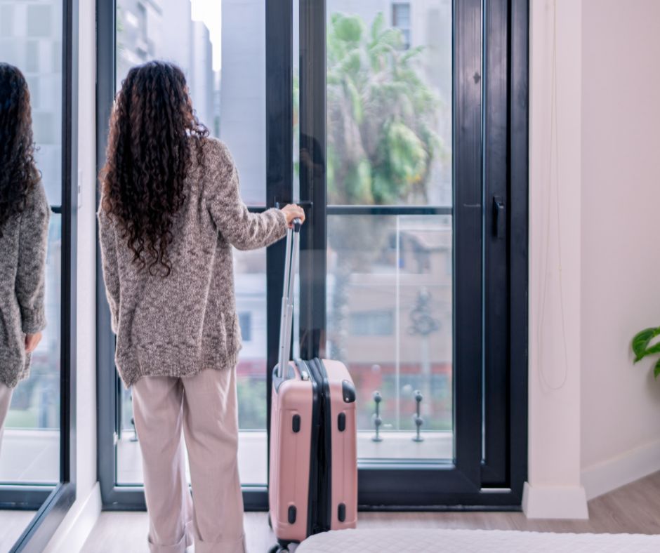 Traveler with a suitcase preparing to leave an apartment, representing extended vacations and concerns about leaving a rental home vacant.