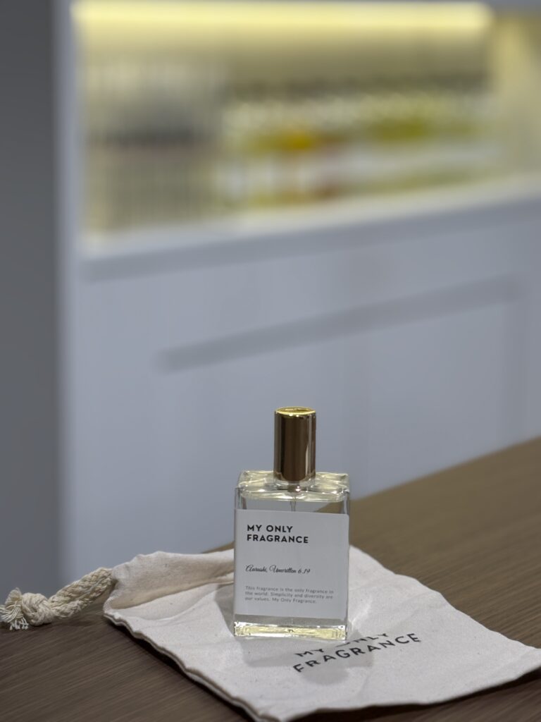 Completed custom perfume bottle with a personalized label resting on a MY ONLY FRAGRANCE drawstring pouch after the fragrance-making workshop.