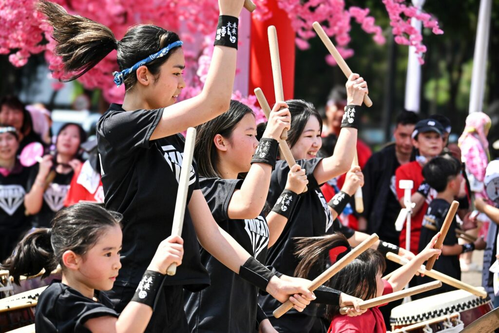Young performers play taiko drums during a lively Japanese neighborhood festival celebration.