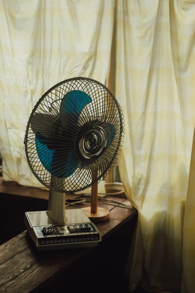 Standing fan circulating cool air in a bedroom during summer.