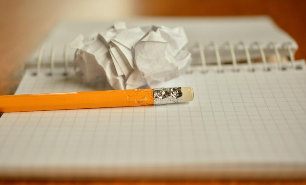 A notebook with a pencil and crumpled paper on a desk, symbolizing homework, studying, and creative thinking during summer vacation.
