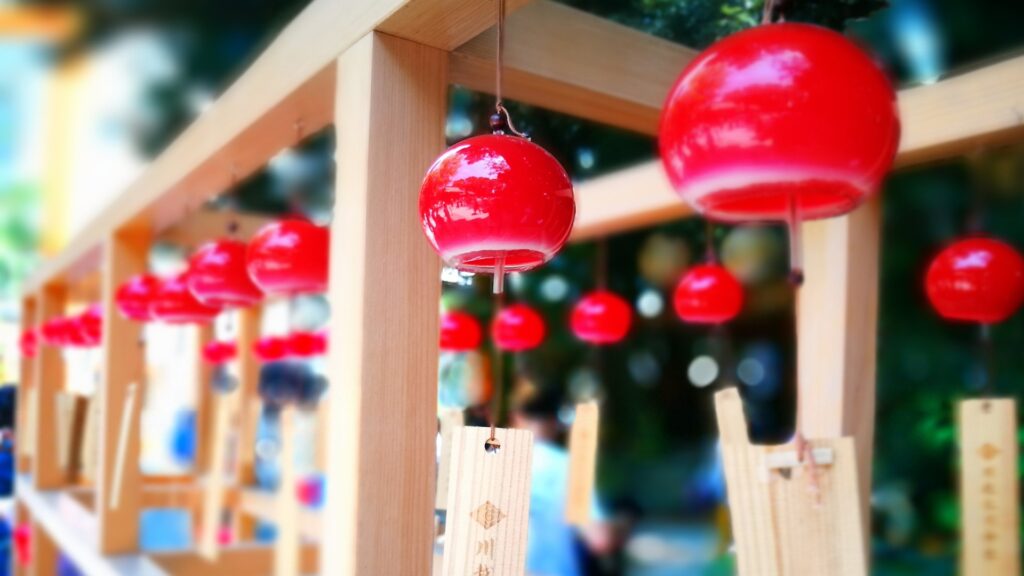 Red Japanese wind chimes hanging outdoors during summer.