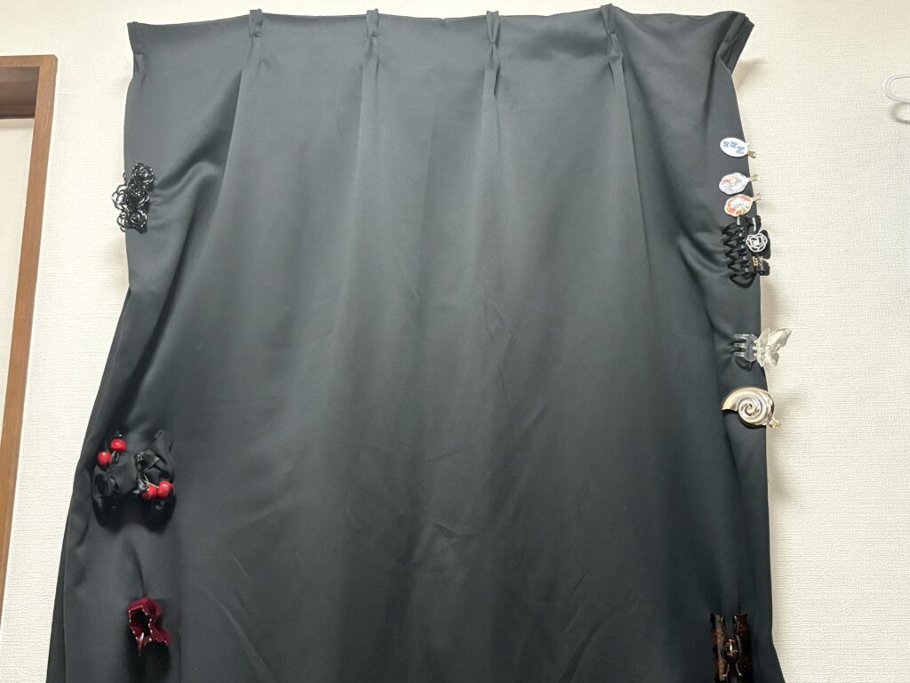 Black blackout curtains covering a window to block sunlight and help keep a room cool.
