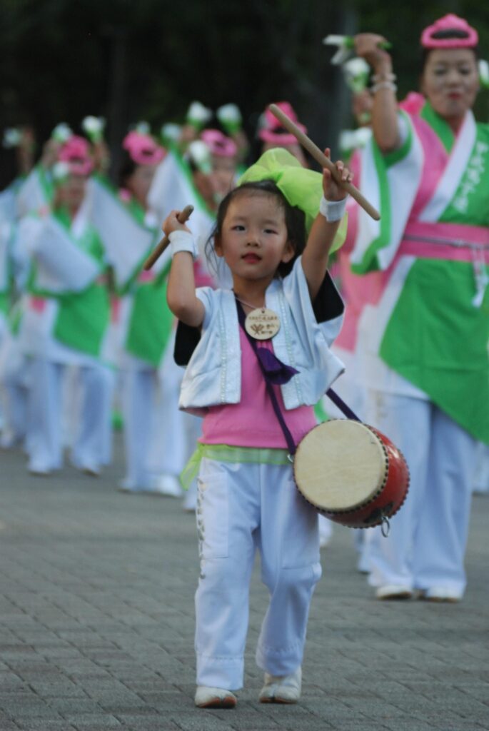 Young taiko drummer performing in a traditional Japanese festival parade.