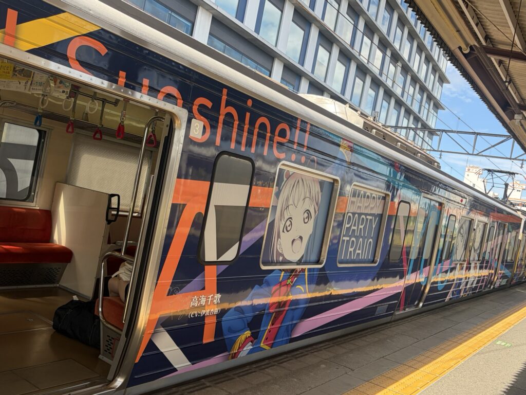 Colorful anime-themed train at a station during the journey to Izu.