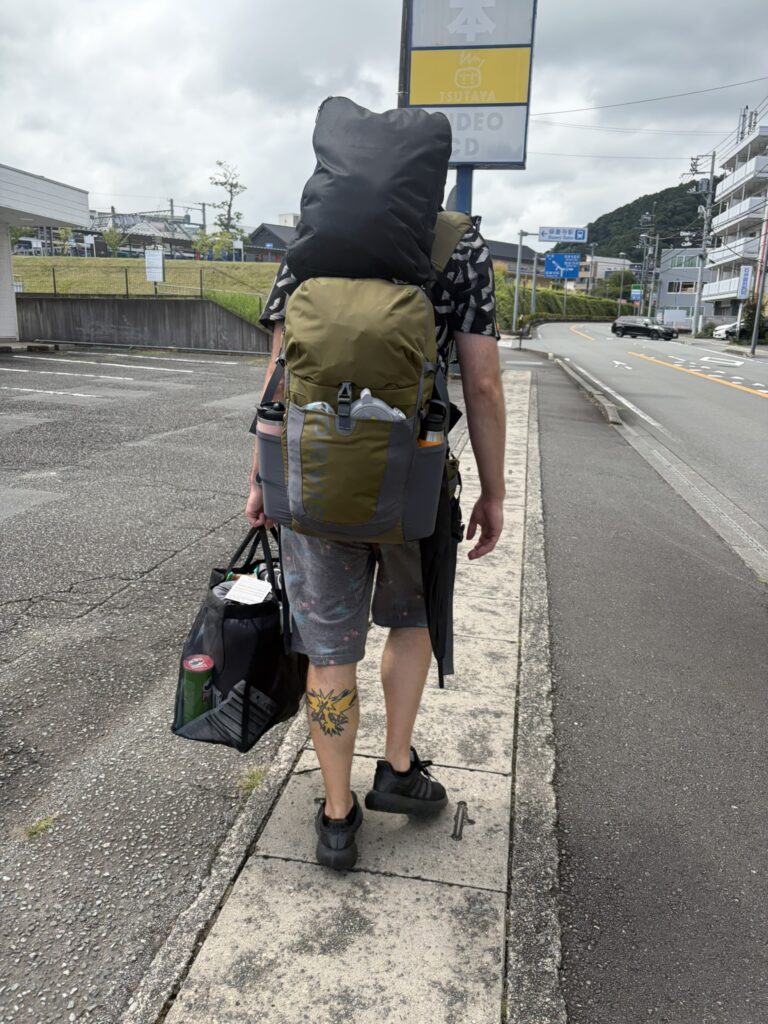 Traveler carrying camping gear and supplies while walking to Koganezaki in Izu.