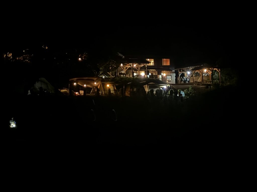 Camp Koganezaki illuminated at night with tents and campsite facilities.