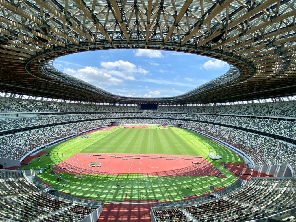Interior of Japan National Stadium in Tokyo with its running track, field, seating, and distinctive open roof.