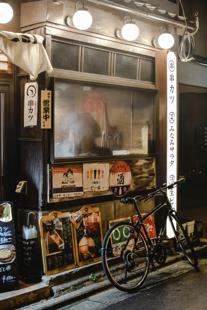 Traditional Japanese restaurant with illuminated signs and a bicycle parked outside.