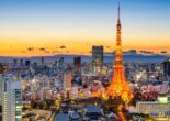 Tokyo Tower illuminated against a colorful sunset, overlooking Tokyo’s city skyline.