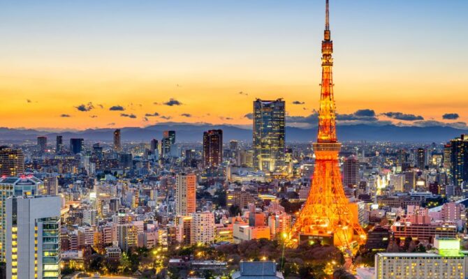 Tokyo Tower illuminated against a colorful sunset, overlooking Tokyo’s city skyline.