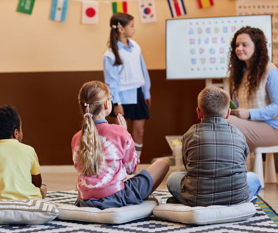 English teacher leading a group lesson for children in a classroom.