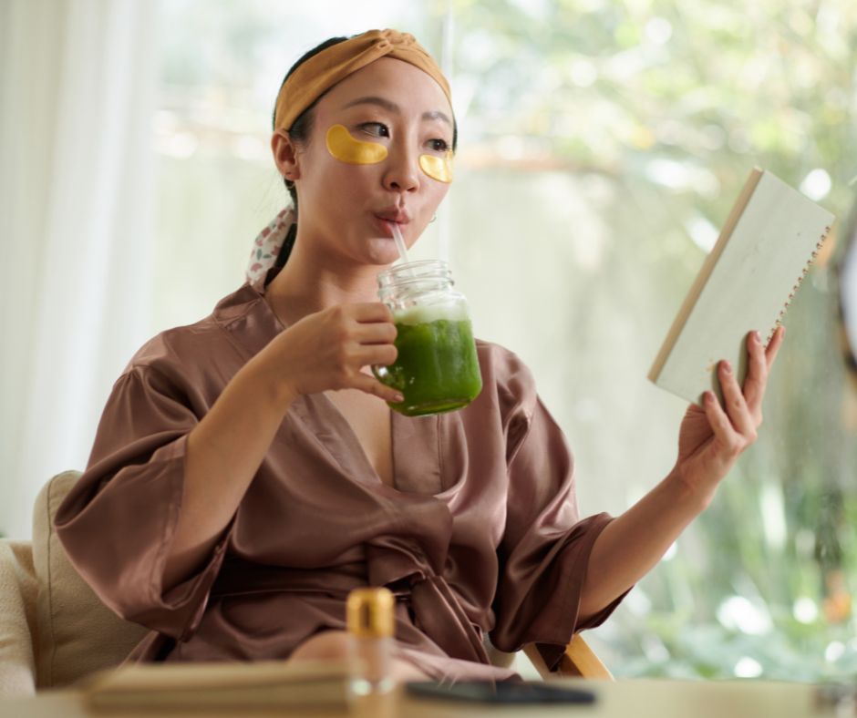 A woman enjoys a green drink while reading a book indoors, relaxing during Japan’s seasonal transition from summer to autumn.