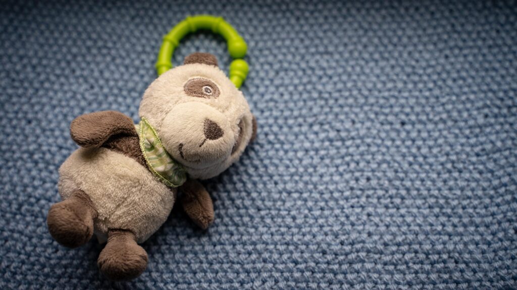 Stuffed panda toy lying on a blue carpet in a childcare setting.