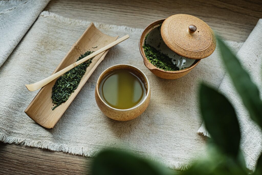 Japanese green tea served in a ceramic cup beside loose tea leaves.