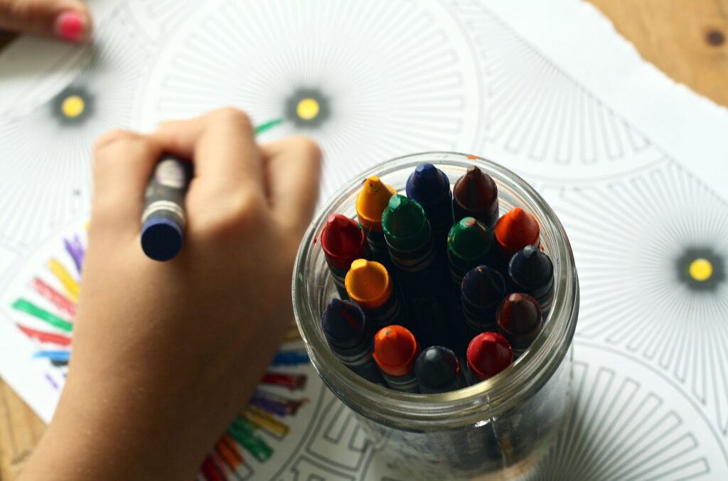 Child coloring a picture with crayons at a table.