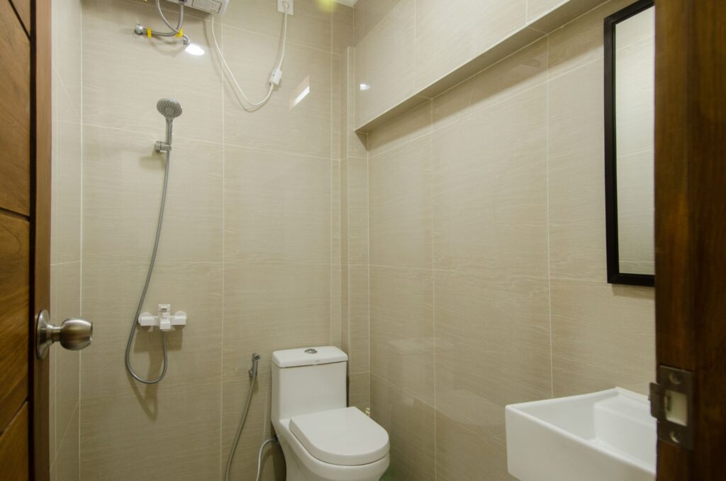 A compact bathroom with a wall-mounted shower, toilet, and sink, illustrating a typical residential bathroom layout.