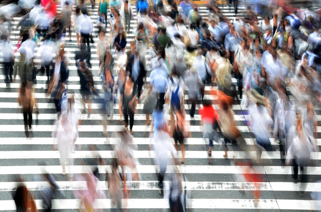Crowds crossing a busy pedestrian intersection in Japan, representing residents and Japan’s changing immigration policies.
