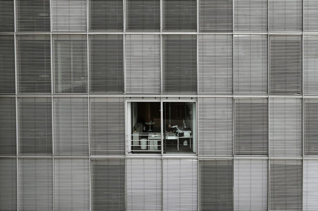 An office worker seen through the window of a modern building, representing professional life and employment.