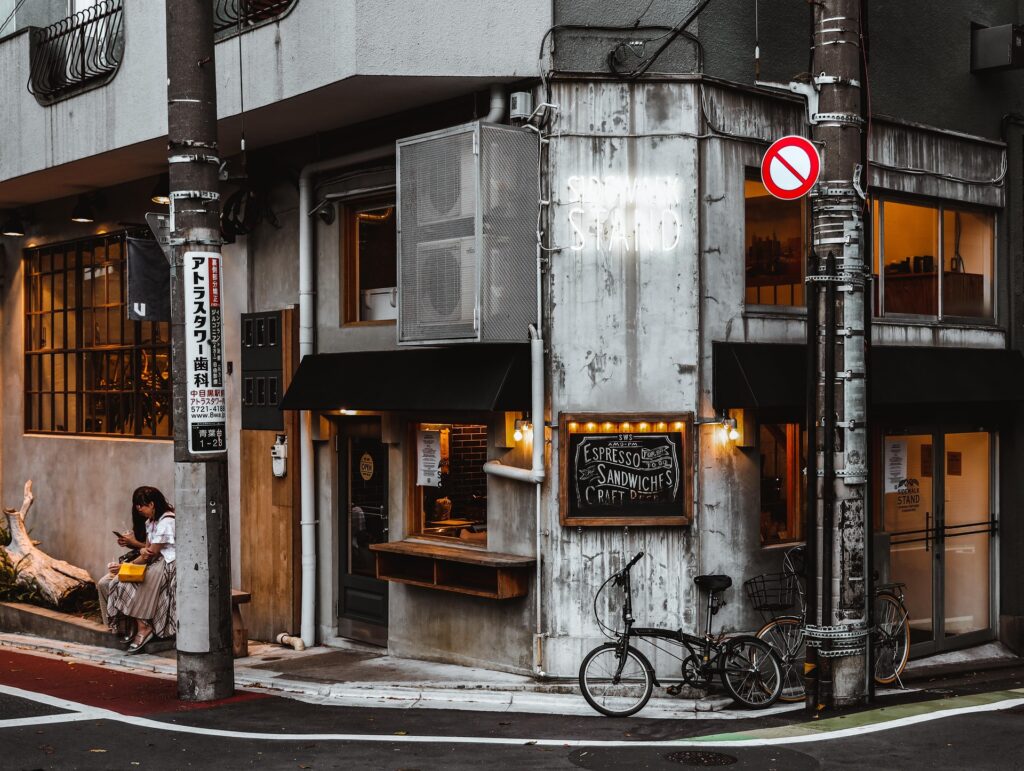 A street corner in Japan featuring small shops and cafés, representing local shopping streets where community Halloween events may take place.