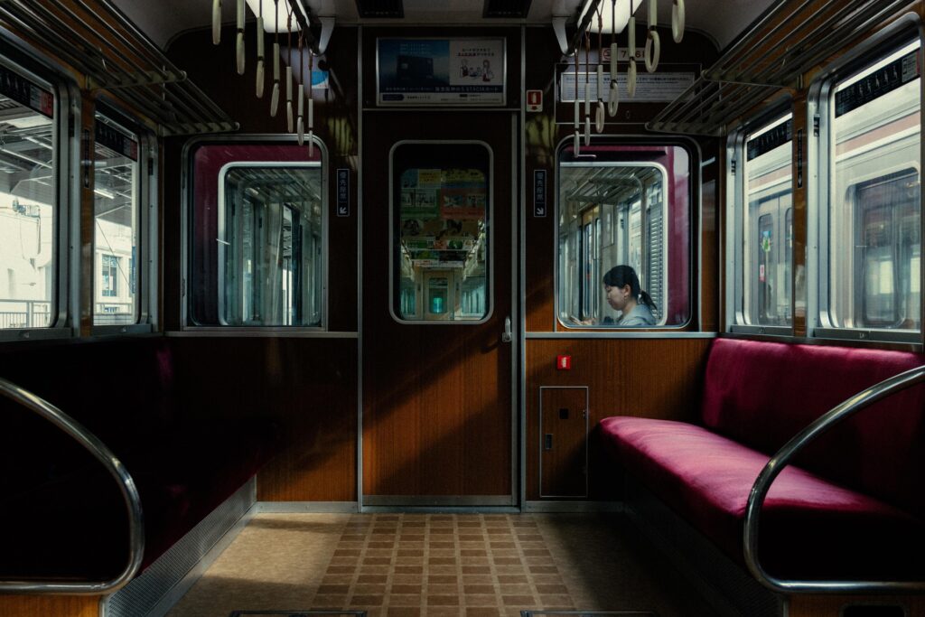 The interior of a Japanese train with a passenger seated inside, representing commuting and working in Japan.