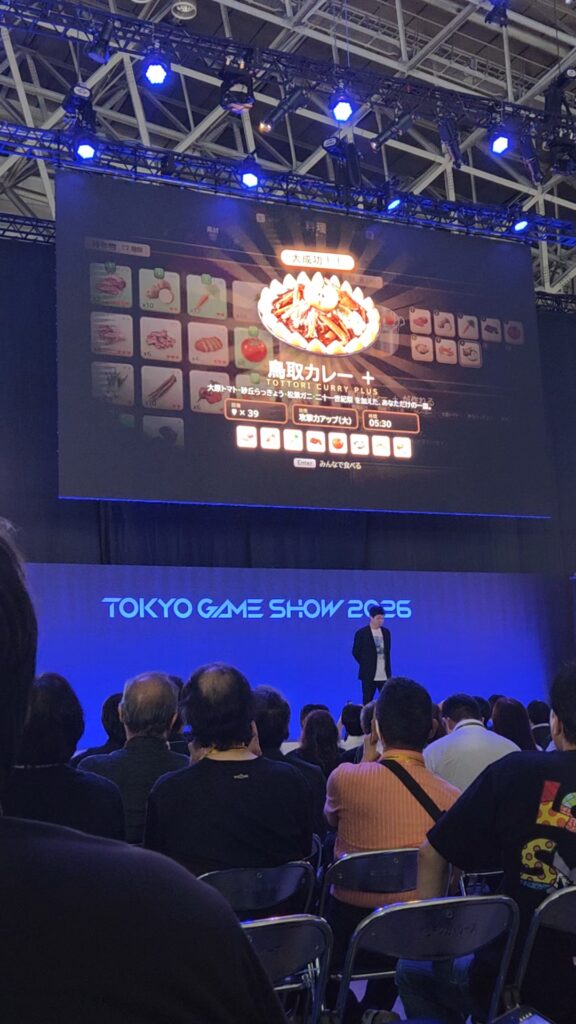 Presenters discussing an earthquake information map displayed on a large screen at Tokyo Game Show 2026.